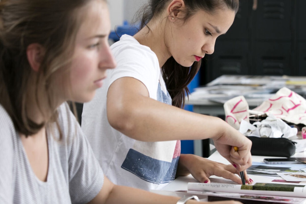 Two people working together at a table in a bright studio-like space.