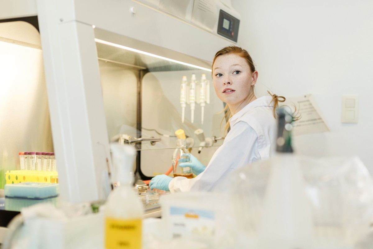 A researcher working at a bright laboratory bench with glassware and equipment.