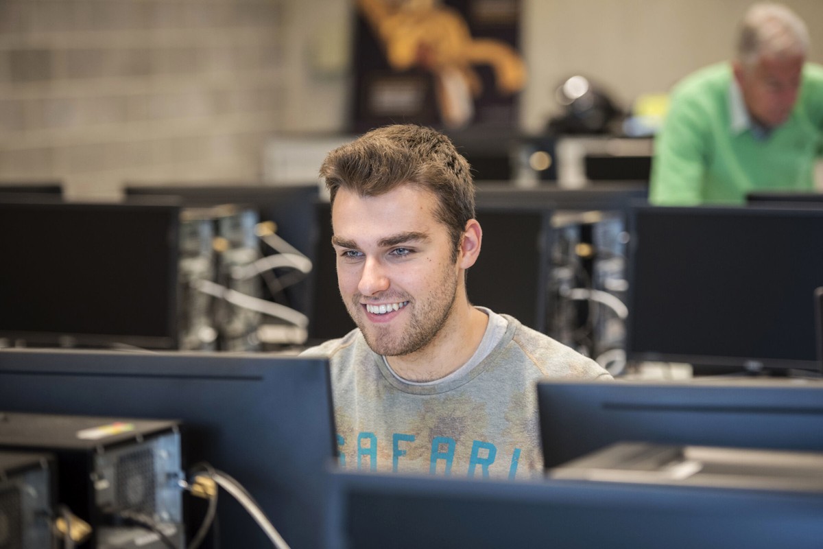 A person working at a computer in a bright, modern indoor space.