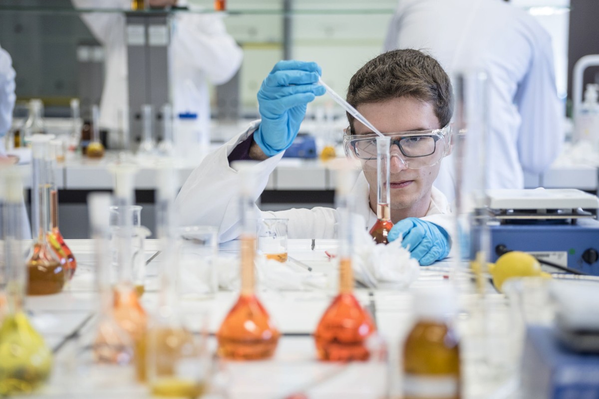A researcher working carefully with glassware and laboratory equipment.